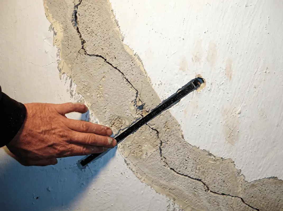 A wall with a large crack is being inspected by a professional in Los Angeles, CA